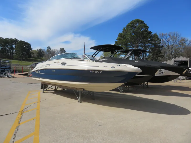 Slide: The Image of 2006 Sea Ray 240 Sundeck boat on display outdoors, clear sky, trees in background. - 1