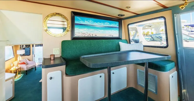Slide: The Image of Interior of a 1994 Shaw 57 boat with green seating and a beach painting. - 10