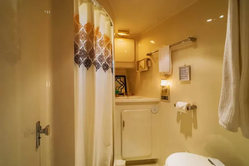 Slide: The Image of Compact bathroom in a 1994 Shaw 57 boat, featuring a shower, sink, and towel rack. - 15