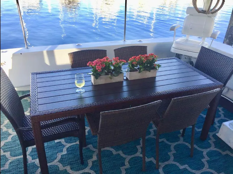 Slide: The Image of Outdoor dining setup on a Shaw 57 yacht, featuring a wooden table, chairs, and floral centerpiece. - 4