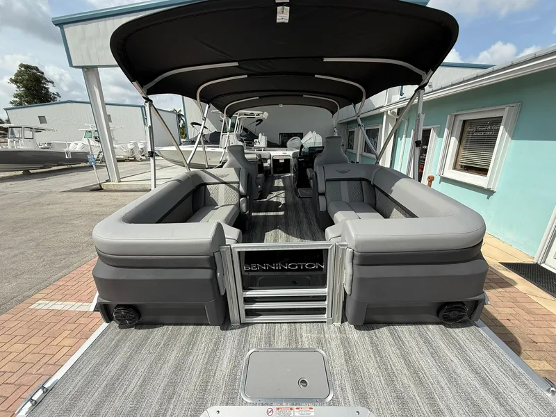 Slide: The Image of 2025 Bennington 22 MFB pontoon boat with spacious seating and canopy, docked near a building. - 4