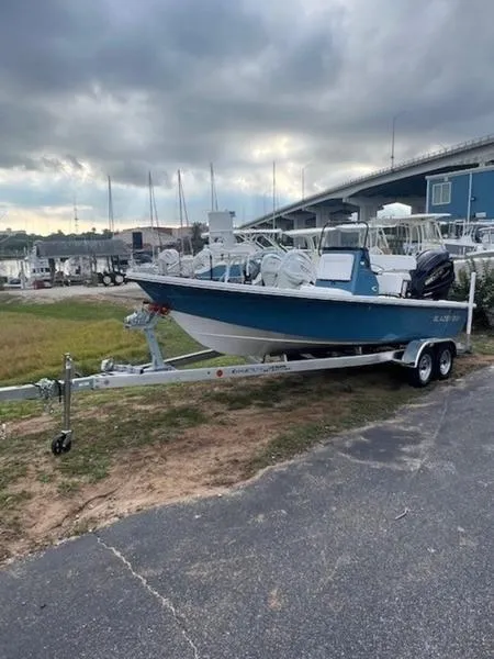 Slide: The Image of 2025 Blazer Bay 2200 boat on trailer near marina under cloudy sky. - 12