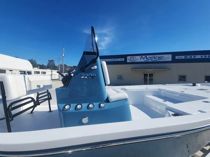 Slide: The Image of 2025 Blazer Bay 2200 boat with blue console, displayed at a marine dealership. - 14