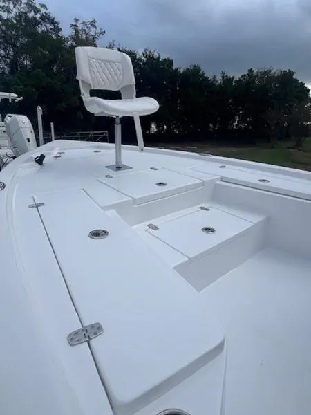 Slide: The Image of 2025 Blazer Bay 2200 boat deck with elevated white seat, surrounded by lush greenery. - 15