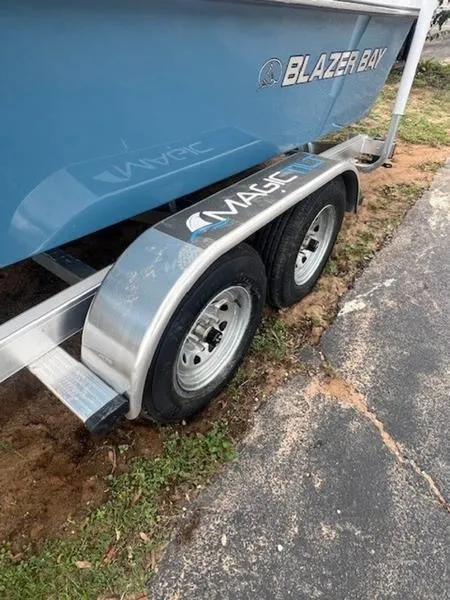 Slide: The Image of 2025 Blazer Bay 2200 boat on a dual-axle trailer, parked on grass and pavement. - 7
