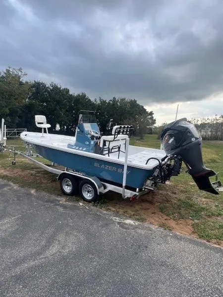 Slide: The Image of 2025 Blazer Bay 2200 boat on trailer, parked outdoors under cloudy sky. - 8