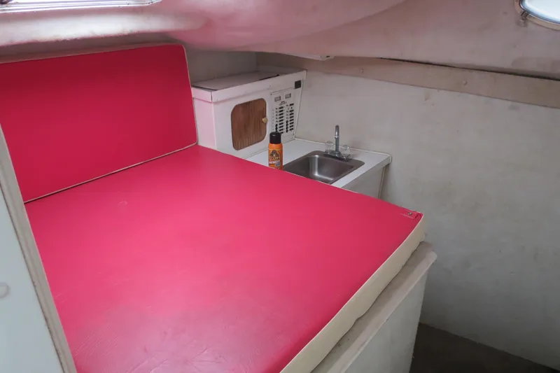 Slide: The Image of 2004 Baha Cruisers 290 King Kat cabin with red seating, sink, and microwave. - 13