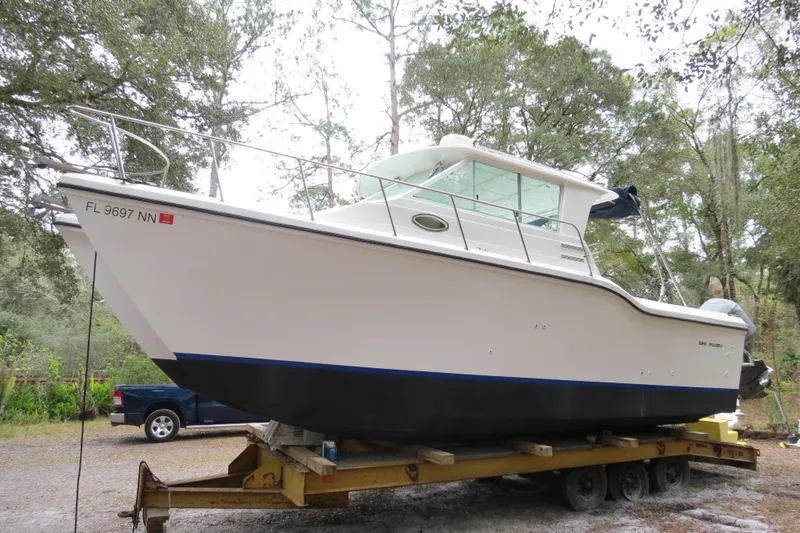 Slide: The Image of 2004 Baha Cruisers 290 King Kat boat on trailer, surrounded by trees. - 9