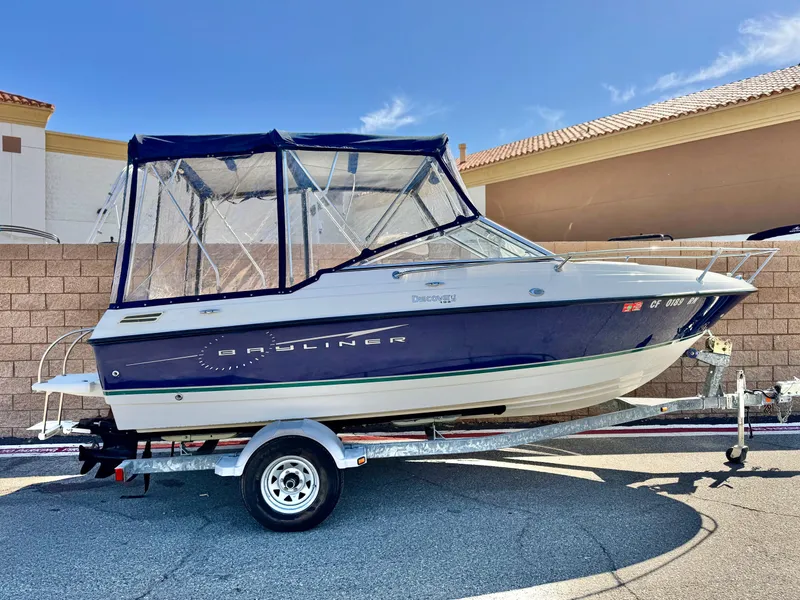 Slide: The Image of 2007 Bayliner 192 Cuddy Discovery boat on trailer with blue canopy, parked outdoors. - 0