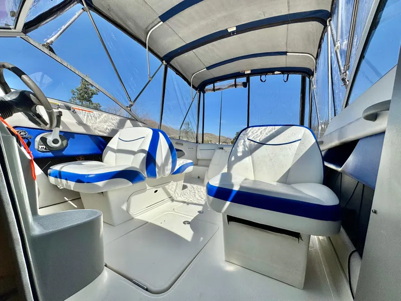 Slide: The Image of 2007 Bayliner 192 Cuddy Discovery interior with blue and white seating under canopy. - 27
