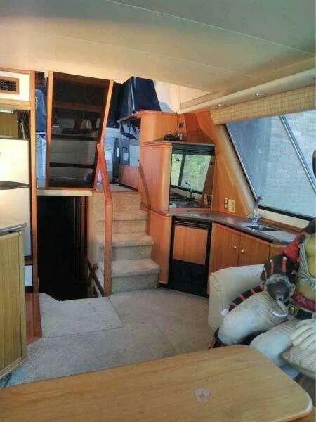 Slide: The Image of Interior of 2000 Bayliner 4788 Pilot House Motoryacht, featuring stairs and cozy seating area. - 18