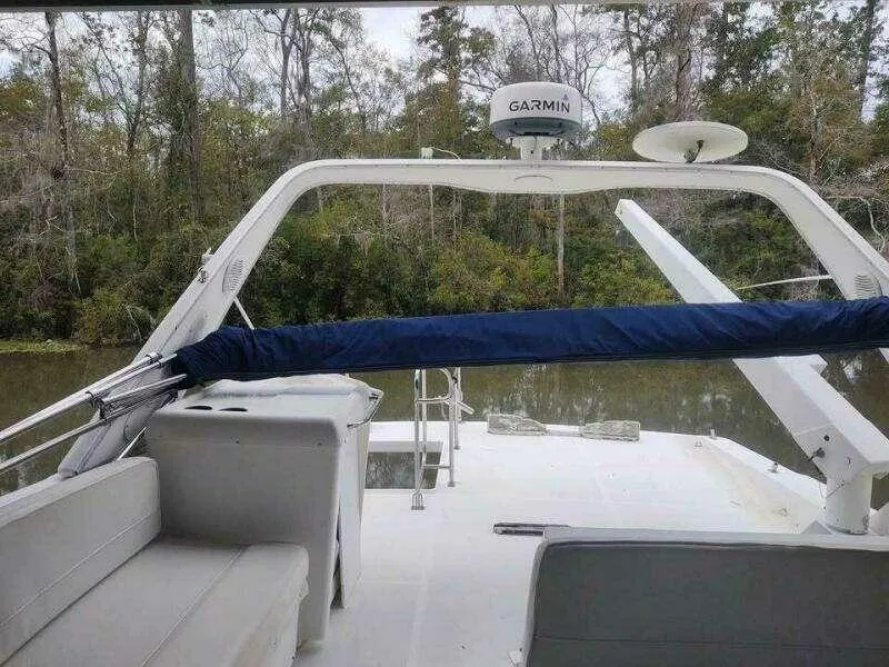 Slide: The Image of Bayliner 4788 Pilot House Motoryacht, 2000 model, with Garmin equipment, docked near a forested riverbank. - 3