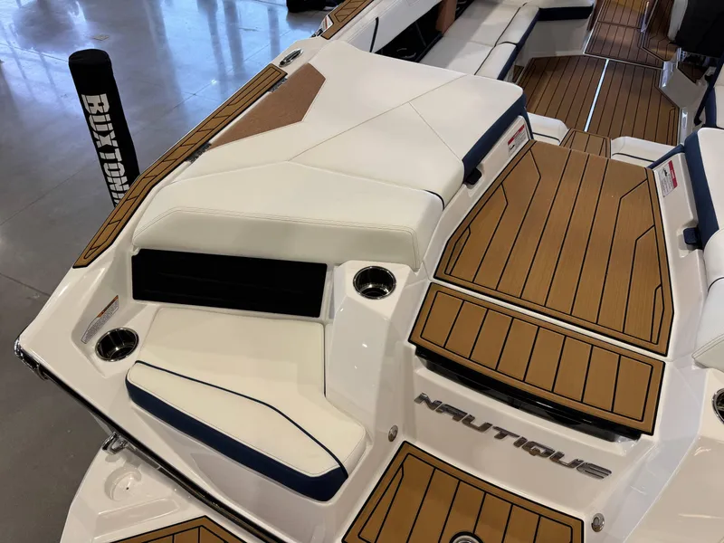 Slide: The Image of 2025 Nautique Super Air Nautique S23 boat interior with teak flooring and white seating. - 11