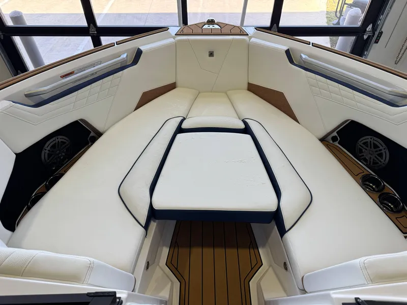 Slide: The Image of 2025 Nautique Super Air Nautique S23 boat interior with luxurious white seating and wood accents. - 16