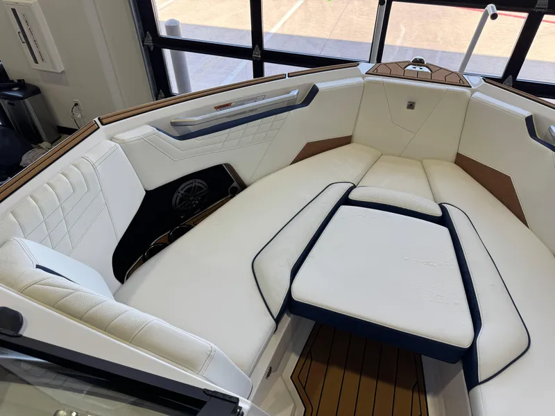 Slide: The Image of 2025 Nautique Super Air Nautique S23 interior with white cushioned seating and wood accents. - 18