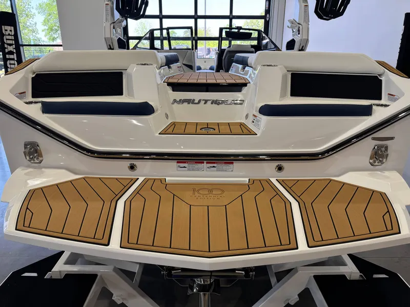 Slide: The Image of 2025 Nautique Super Air Nautique S23 boat with teak deck and sleek design in showroom. - 7
