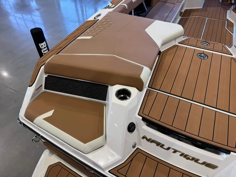 Slide: The Image of 2025 Nautique Super Air Nautique GS24 boat interior with brown and white seating, teak flooring. - 12
