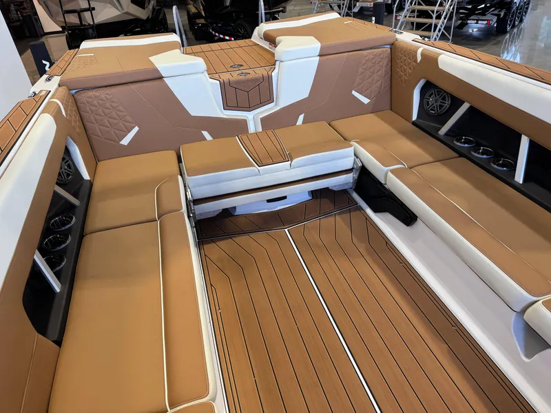 Slide: The Image of 2025 Nautique Super Air Nautique GS24 interior with tan and white seating, cup holders, and speakers. - 16