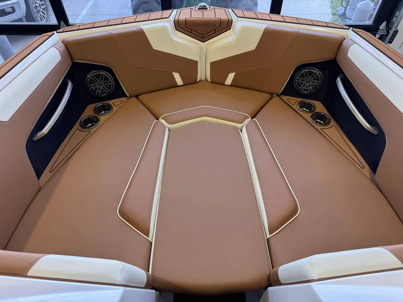 Slide: The Image of 2025 Nautique Super Air Nautique GS24 interior with tan and white seating, cup holders, and speakers. - 17