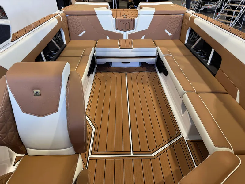 Slide: The Image of 2025 Nautique Super Air Nautique GS24 interior with tan and white seating, wood-style flooring. - 22