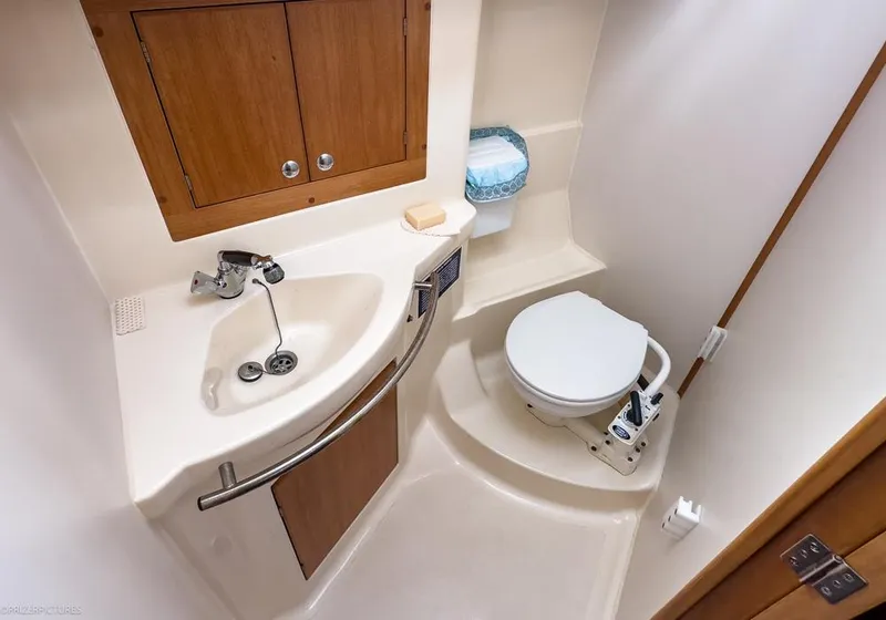 Slide: The Image of Compact bathroom in 2011 Elan Impression 384 yacht with sink, toilet, and wooden cabinetry. - 22