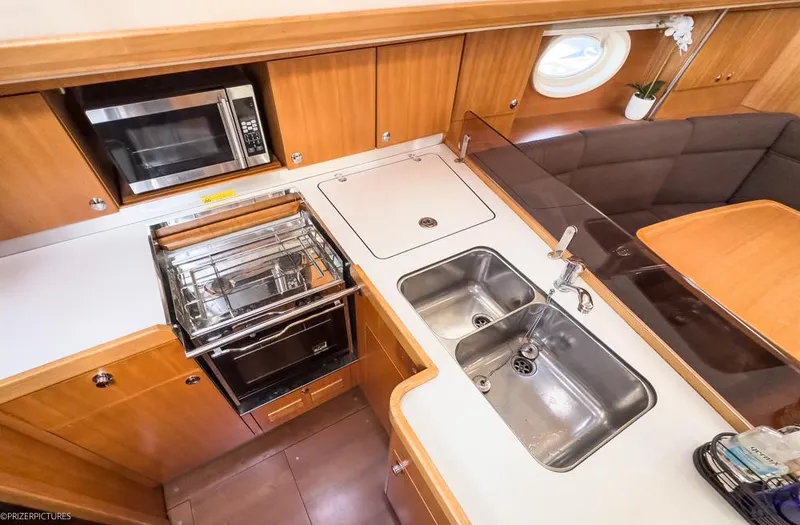 Slide: The Image of 2011 Elan Impression 384 yacht kitchen with dual sinks, stove, and microwave. - 26