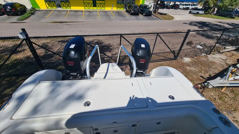 Slide: The Image of 2009 World Cat 250 DC boat with dual outboard motors, parked near a fenced area. - 21