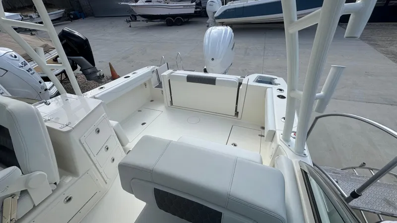 Slide: The Image of 2025 Cobia 240 Dual Console boat interior with seating and storage, docked outdoors. - 12