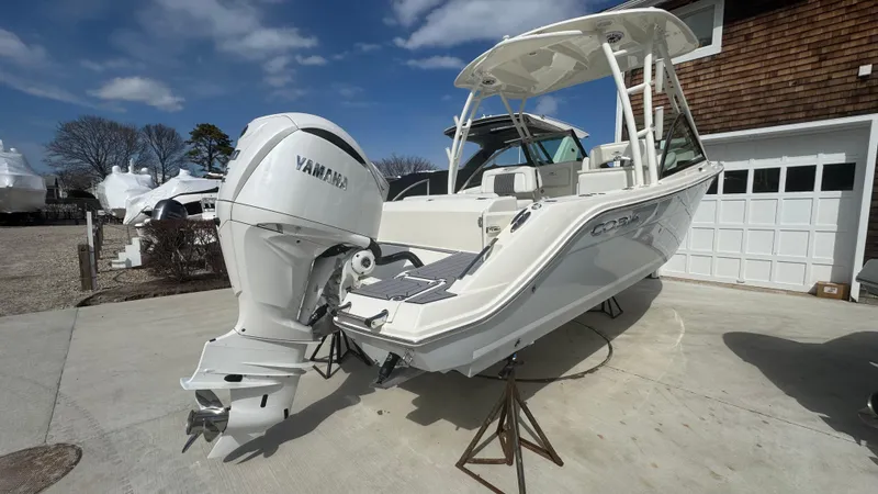 Slide: The Image of 2025 Cobia 240 Dual Console boat with Yamaha engine on display outdoors. - 2