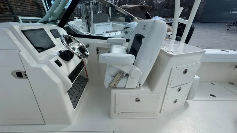 Slide: The Image of 2025 Cobia 240 Dual Console boat interior with helm, steering wheel, and seating. - 23