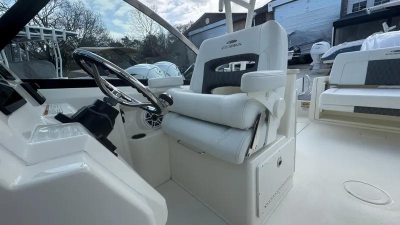 Slide: The Image of 2025 Cobia 240 Dual Console boat interior with steering wheel and white seating. - 24