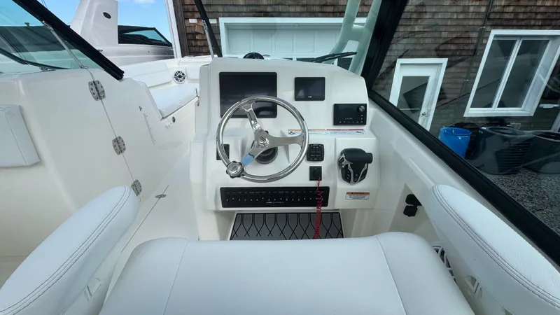 Slide: The Image of 2025 Cobia 240 Dual Console boat cockpit with steering wheel and control panel. - 25