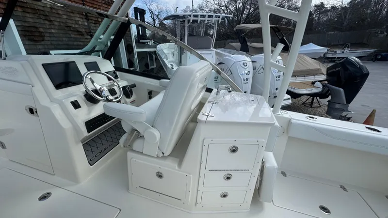 Slide: The Image of 2025 Cobia 240 Dual Console boat interior with helm, seating, and storage drawers. - 26