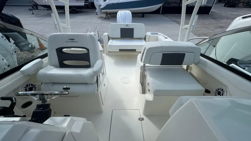 Slide: The Image of 2025 Cobia 240 Dual Console boat interior with white seating and steering wheel. - 27