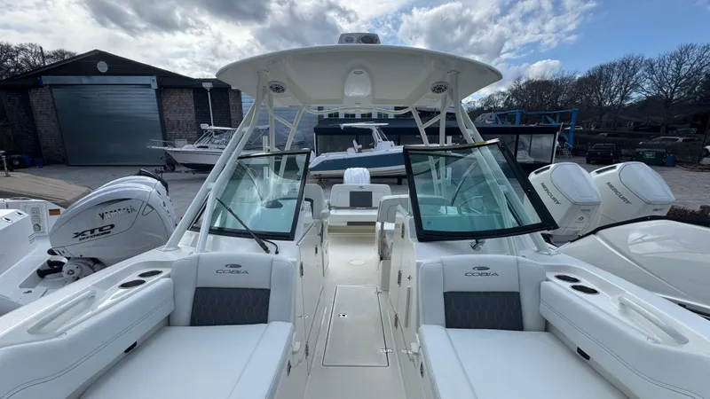 Slide: The Image of 2025 Cobia 240 Dual Console boat with spacious seating and twin engines, docked outdoors. - 35