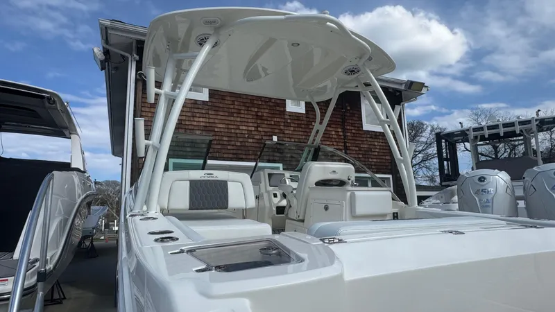 Slide: The Image of 2025 Cobia 240 Dual Console boat with sleek design, parked outdoors under a blue sky. - 5