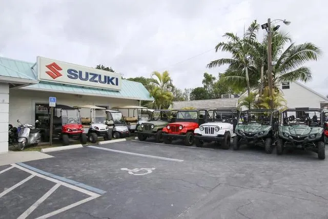 Slide: The Image of Outdoor display of Suzuki vehicles and ATVs at a dealership, surrounded by palm trees. - 36