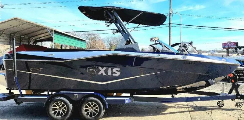 Slide: The Image of 2024 Axis Core Series T235 boat on trailer, sleek design, black exterior, parked outdoors. - 2
