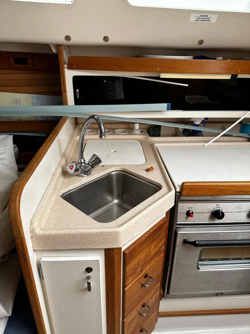 Slide: The Image of 1997 Catalina 28 MkII yacht kitchen with sink, stove, and wooden cabinetry. - 16