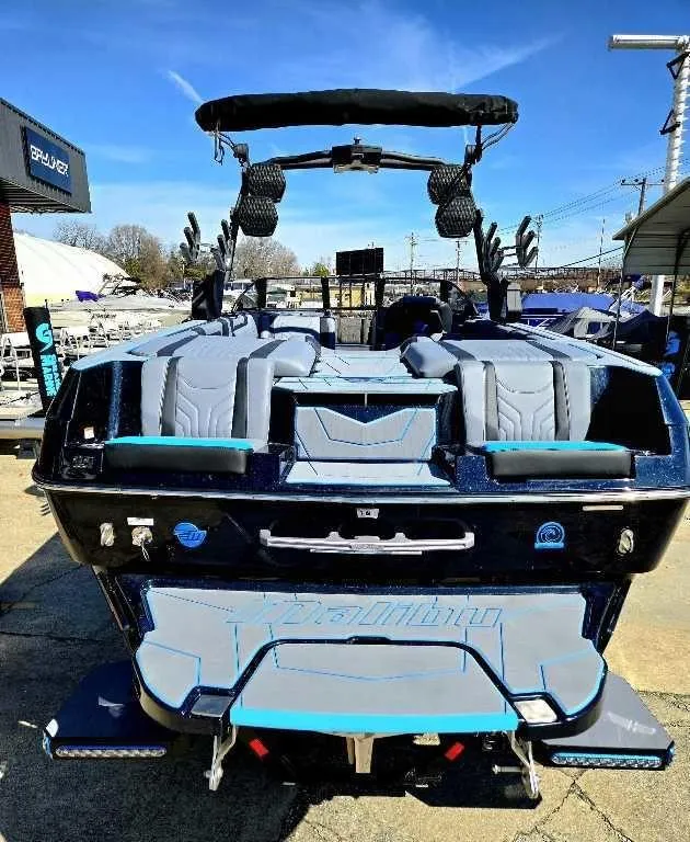 Slide: The Image of 2025 Malibu Wakesetter 25 LSV boat, rear view, in a marina setting. - 4
