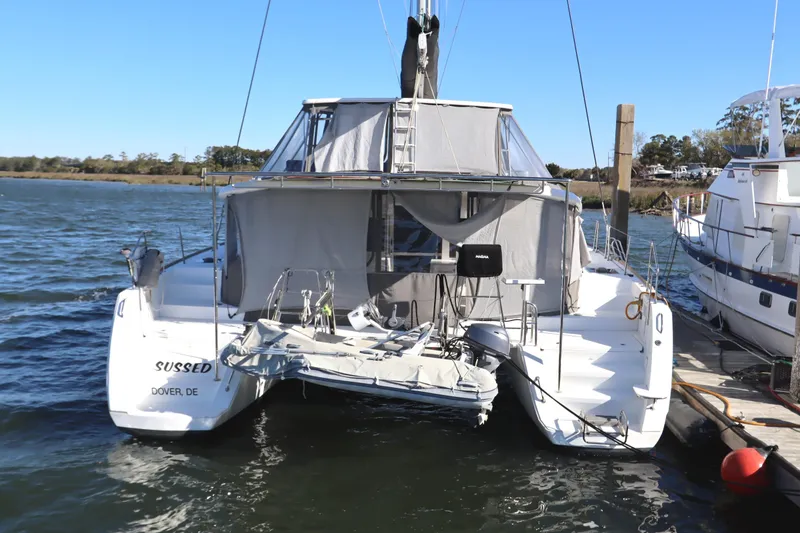 Slide: The Image of 2017 Lagoon 450 F catamaran docked, rear view, with protective canopy and calm waters. - 4