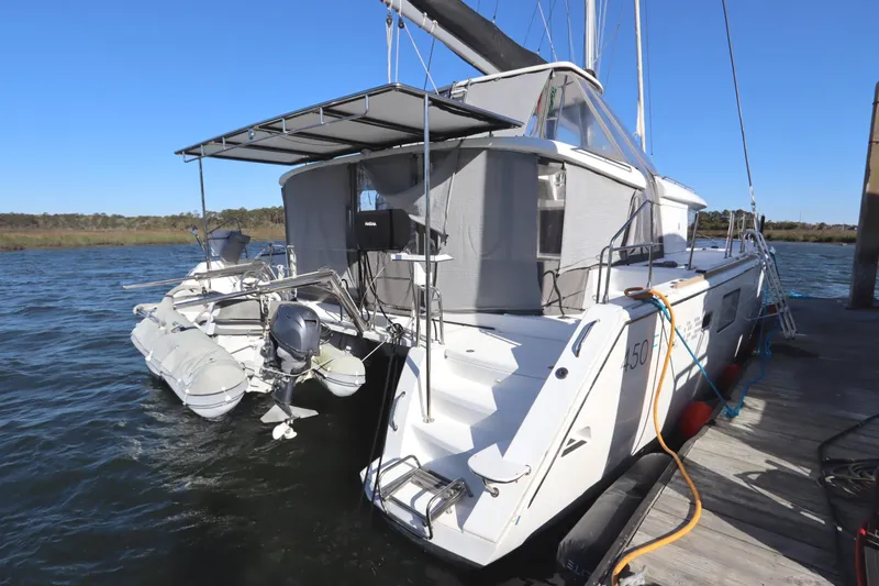 Slide: The Image of 2017 Lagoon 450 F catamaran docked with dinghy, featuring spacious deck and canopy. - 5