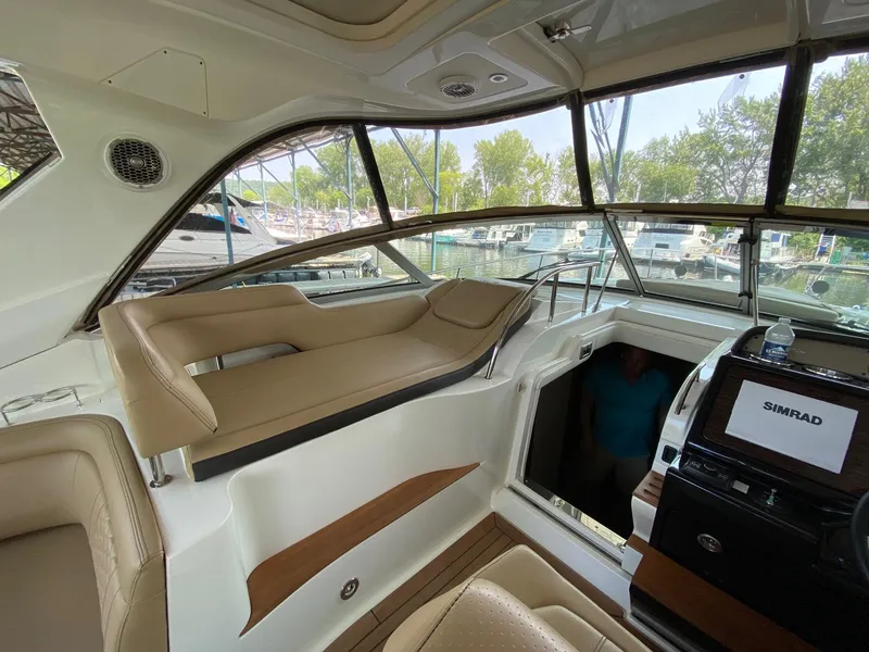 Slide: The Image of 2018 Sea Ray Sundancer 350 interior with beige seating and navigation equipment. - 16