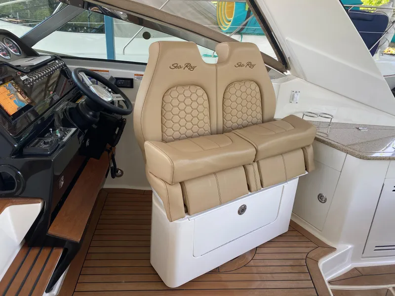 Slide: The Image of 2018 Sea Ray Sundancer 350 helm with beige leather seats and wooden flooring. - 22