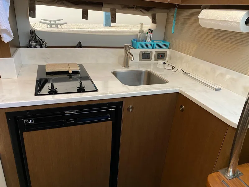 Slide: The Image of 2018 Sea Ray Sundancer 350 yacht kitchen with stove, sink, and compact fridge. - 26