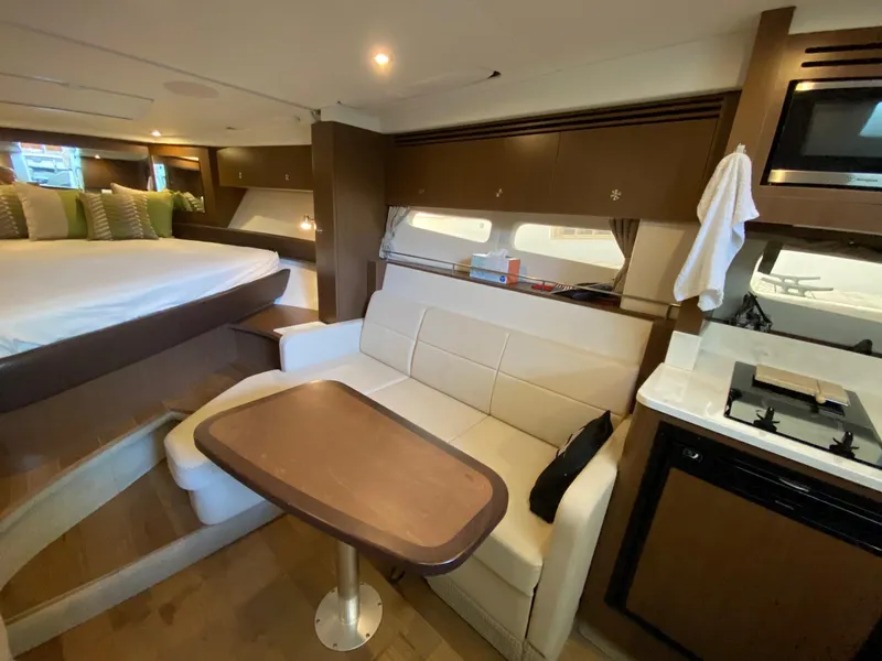 Slide: The Image of 2018 Sea Ray Sundancer 350 interior with bed, sofa, table, and kitchenette. - 27