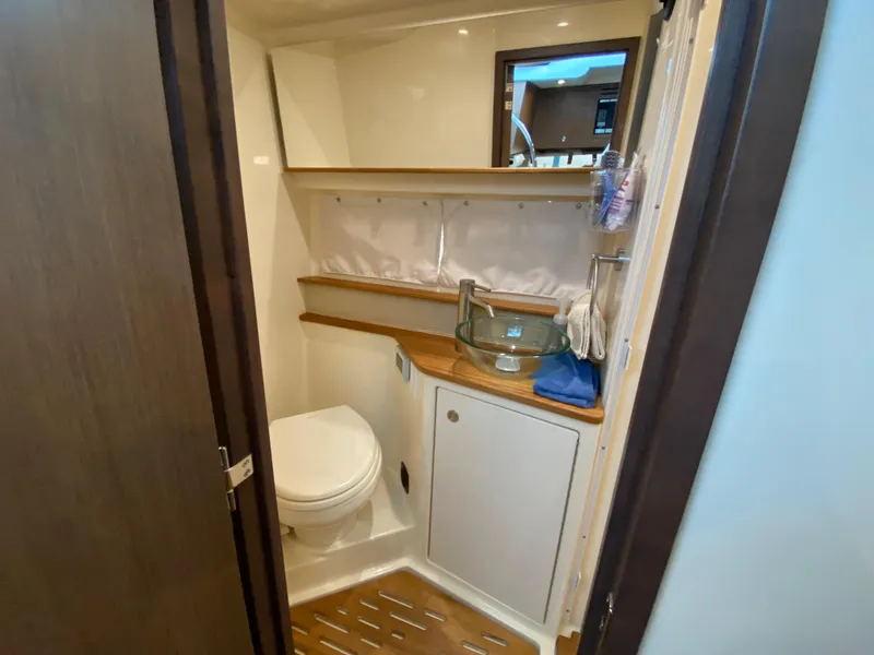 Slide: The Image of 2018 Sea Ray Sundancer 350 bathroom with toilet, glass sink, and wooden shelves. - 40