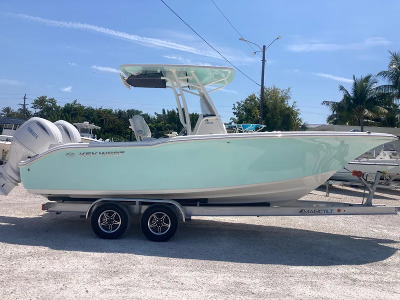 Slide: The Image of 2025 Key West 244CC boat on trailer, light blue hull, parked outdoors. - 0