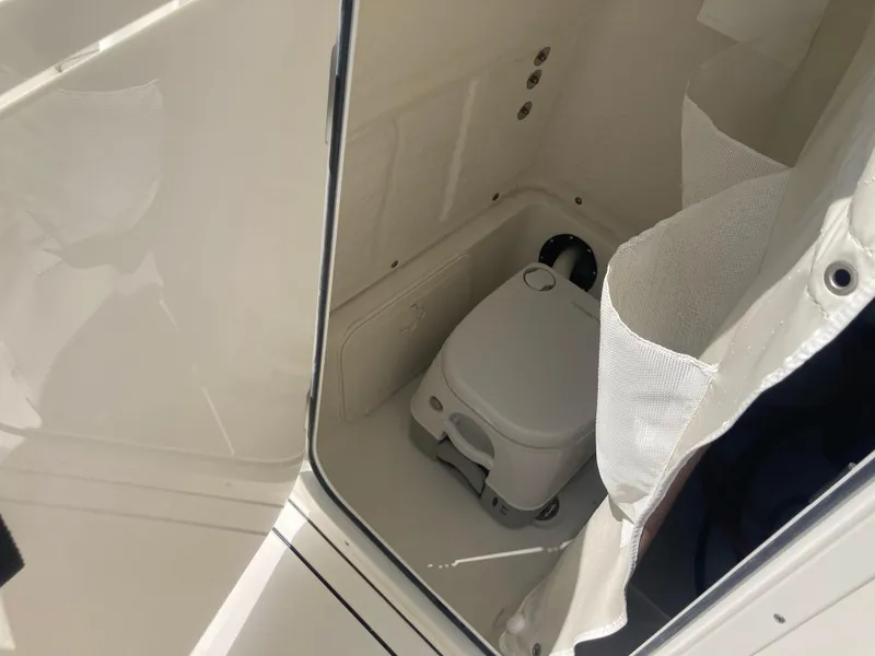 Slide: The Image of Portable toilet inside 2025 Key West 244CC boat cabin, featuring compact design and privacy curtain. - 14