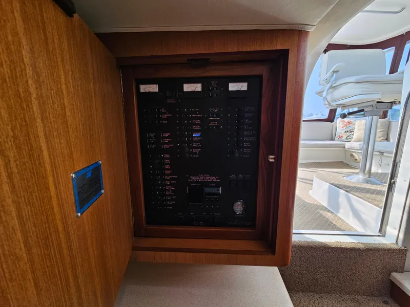 Slide: The Image of Electrical panel inside a 1998 Ocean Yachts 40, featuring wooden cabinetry and modern seating area. - 24